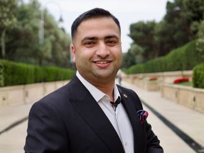 Dr. Hamza Tariq wearing a dark suit outdoors on a landscaped walkway.